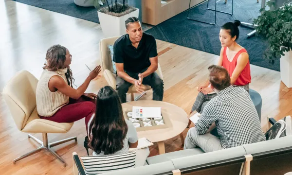 Group of people in discussion, seated in a circle in a modern office lounge